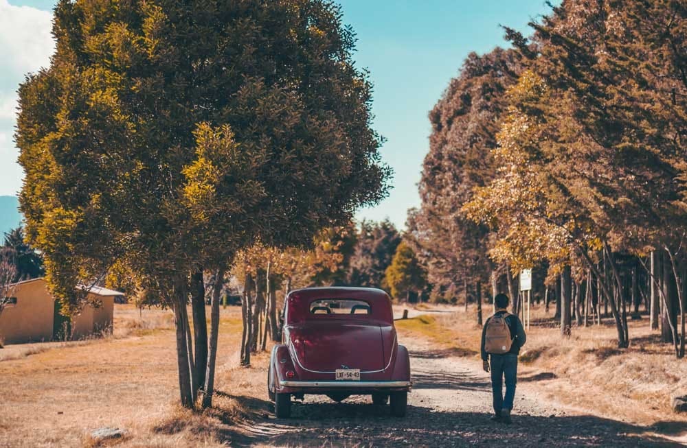 Conducir Australia chico de espaldas y al lado un coche rojo vintage